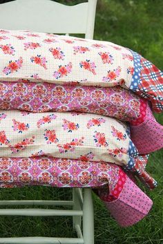 four pillows stacked on top of each other in front of a white chair with green grass