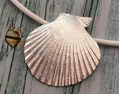 a pink shell sitting on top of a wooden floor next to a white cord and a piece of wire