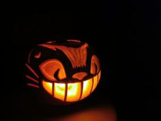 a carved pumpkin with an evil cat face on it's side, lit up in the dark