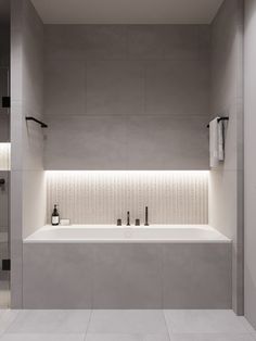 a white bath tub sitting next to a shower in a bathroom with lights on the wall