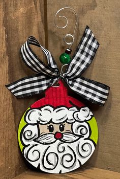 a christmas ornament hanging on the side of a wooden wall with a black and white checkered ribbon