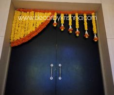 an entrance decorated with yellow and orange garlands, flowers and candles on the door