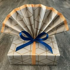 an open gift box with a blue ribbon tied around the top and inside, sitting on a wood floor