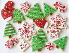 decorated christmas cookies on a white plate with red, green and white decorations in the shape of trees