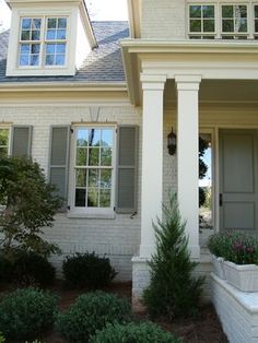 a white house with green shutters and flowers