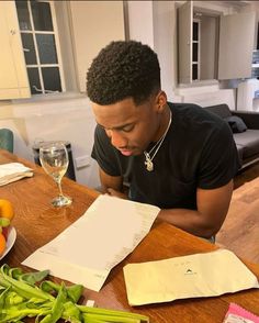 a man sitting at a table with vegetables and papers in front of him looking down