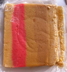 a piece of cake with red and yellow stripes on it sitting on plastic wrapper