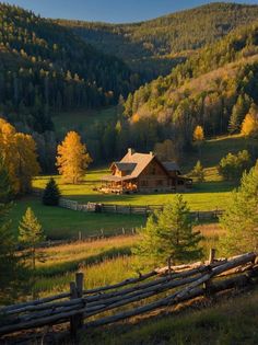 a large house in the middle of a field surrounded by trees and mountains with fall colors