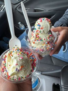 two scoops of ice cream with sprinkles in plastic cups on a car dash board