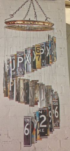 an art piece is hanging on the wall in front of a brick wall with numbers and letters