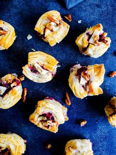 several pastries with nuts and cranberry toppings on a blue surface