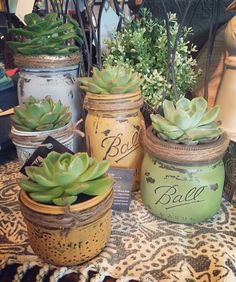 four jars with succulents are sitting on a table