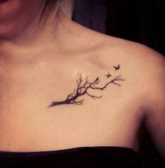 a woman's chest with birds flying around the tree branch on her left shoulder