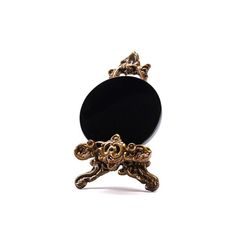 an ornate black and gold ring on a white background