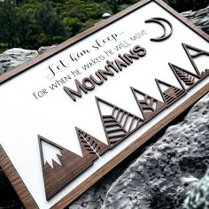 a sign that is on the side of a rock with trees in the background and words below it