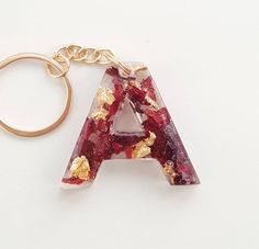 a red and gold letter shaped keychain on a white surface