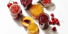 four jars filled with different types of fruit jams and one has peaches on the side