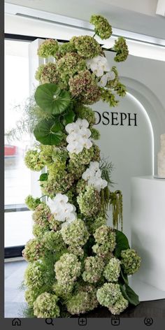 a white and green flower arrangement on display in front of a sign