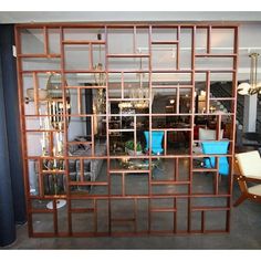 a room divider made out of wood and glass with blue chairs in the background