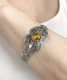 Yellow Citrine Silver Filigree Bangle Cuff Bracelet, 925 Sterling Silver Artisan Handmade Filigree Gothic Women Bangle Cuff Jewelry Yellow stone cuff, silver gift for mom her, statement bracelet, one of a kind cuff, vintage bold bangle, anniversary gift her, wedding gift her, bridesmaid gift, goth women bangle Material: 925 Sterling Silver ( NICKEL FREE ) Gemstone: Yellow Citrine 12x16 mm. Bracelet Length: 20.3 cm // 8 Inches Bracelets Width: 3 cm // 1.2 Inches FAST AND TRACKABLE SHIPPING FOR ALL EU COUNTRIES AND USA. It sounds like you're describing a beautiful piece of jewelry! A yellow citrine silver filigree bangle cuff bracelet made from 925 sterling silver with artisan handmade filigree and a gothic design. Citrine is a lovely yellow gemstone known for its vibrant color and positive Filigree Bangle, Gothic Women, Gothic Bracelet, Filigree Bracelet, Goth Women, Yellow Gemstones, Vintage Inspired Jewelry, Cuff Jewelry, Yellow Citrine