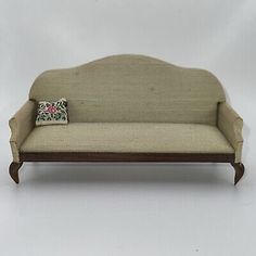 a small couch with a pillow on it's arm and back rest, sitting against a white background