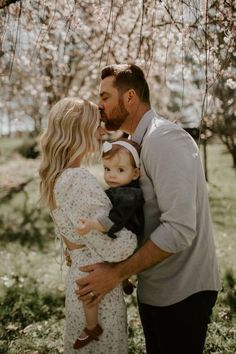 a man and woman holding a baby in their arms