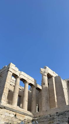 the part of an ancient building with columns and pillars on it's sides, against a blue sky