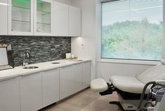 an office with white cabinets and chairs in front of a window that has blind shades on it