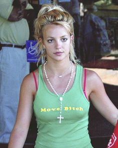 a woman wearing a green tank top with a cross on the chest and pearls around her neck