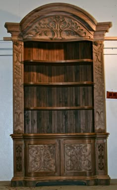 an old wooden bookcase with carvings on the front and back sides, in a room