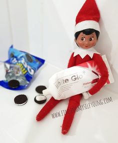 an elf is holding a toothpaste tube and sitting on a table next to other items