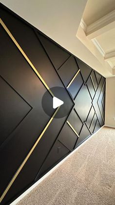 an empty room with black walls and gold trimmings on the wall, along with carpeted flooring