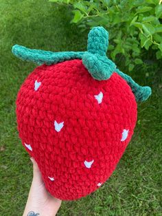 a hand holding up a crocheted strawberry