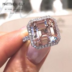 someone is holding an engagement ring with a fancy pink diamond in it's center