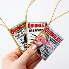 a person holding three small magazines in their hand with string attached to them, on a white background