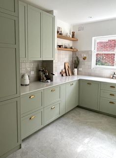 a kitchen filled with lots of green cabinets and counter top space next to a window