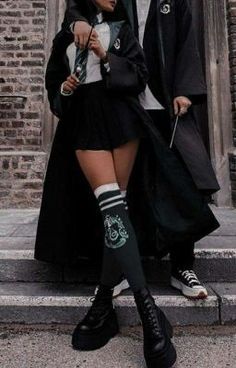 two people dressed in harry potter costumes standing on the street with one holding an umbrella