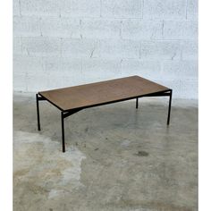 a coffee table sitting on top of a cement floor next to a white brick wall