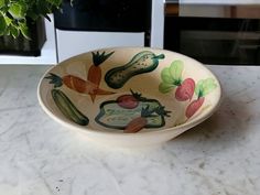 a bowl with vegetables painted on it sitting on a kitchen counter next to an oven