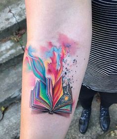 a person with a tattoo on their arm and an open book in the middle of it