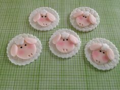 four pink sheep are sitting in the middle of three small white sheep on a green tablecloth