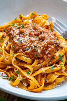 a white plate topped with pasta covered in sauce and parmesan cheese