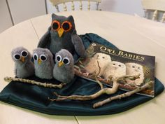 three stuffed owls sitting on top of a table next to an owl book