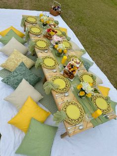 a long table is set with yellow and green plates, napkins, and flowers