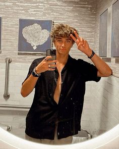 a man taking a selfie in front of a bathroom mirror with his cell phone