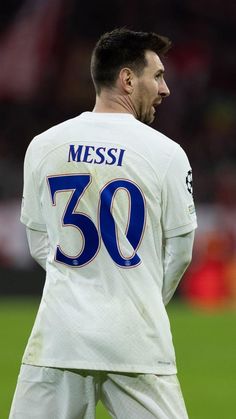 a man standing on top of a soccer field wearing a white shirt and blue numbers