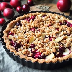 a pie with cranberries and apples in it sitting on a table next to other fruit