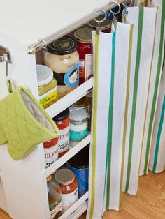 an open cabinet filled with lots of food and kitchen supplies on top of a hard wood floor