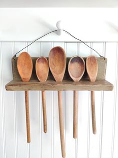 five wooden spoons are hanging on a wall