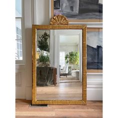 a mirror sitting on top of a hard wood floor next to a wall mounted planter